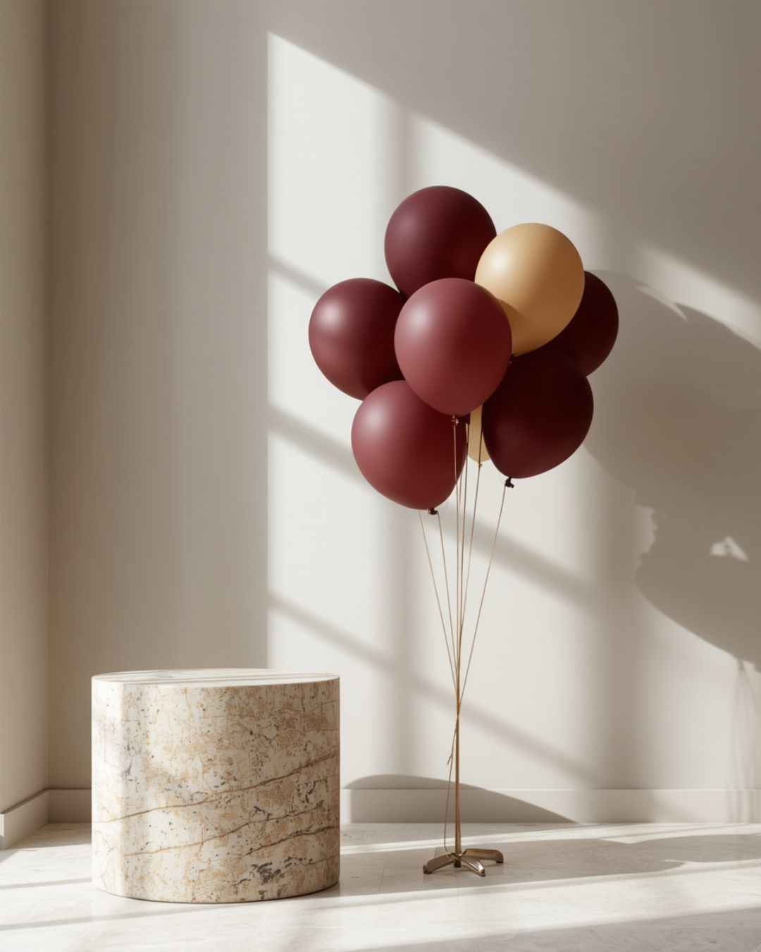 A curated wholesale cluster of Atlore matte maroon and beige balloons displayed next to a jewelry counter pedestal.