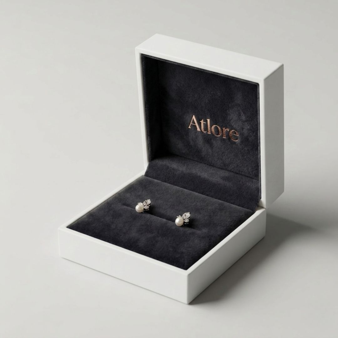 Minimalist white paper-plastic hybrid earring box showcasing a contrasting charcoal black velvet inner display pad and rose gold branding.