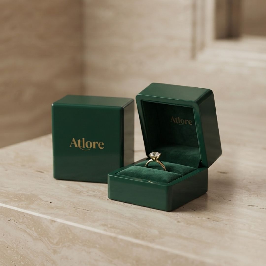 Open view of a deep emerald green velvet-lined Atlore ring box with a gold diamond ring